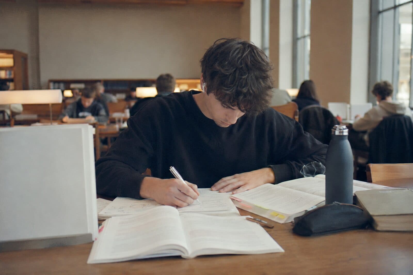 Ein Student lernt mit Büchern und Notizen an einem Tisch in der Bibliothek